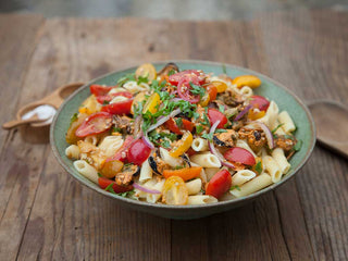 Bright, colorful bowl of penne pasta with cherry tomatoes, red onion, basil, and mussels