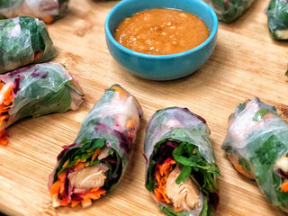 Colorful vegetable and salmon spring rolls in rice paper wrappers and a bowl of dipping sauce