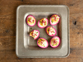 Beet-Pickled deviled eggs on a square metal tray on wooden table