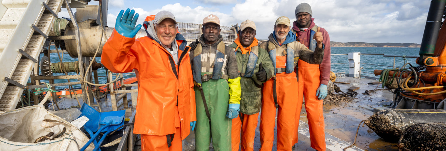 workers on a boat in ocean waving to the camera