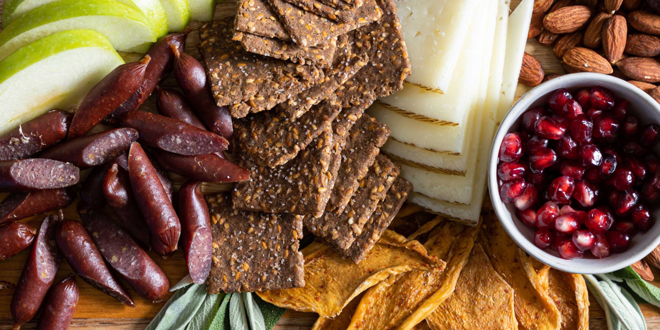 A full crudite board covered with Patagonia Provisions Breadfruit Crackers, fruits, nuts, olives and cheeses