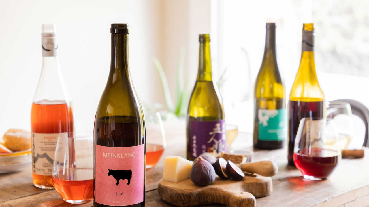 A collection of Patagonia Provisions wine bottles and glasses on a wooden table