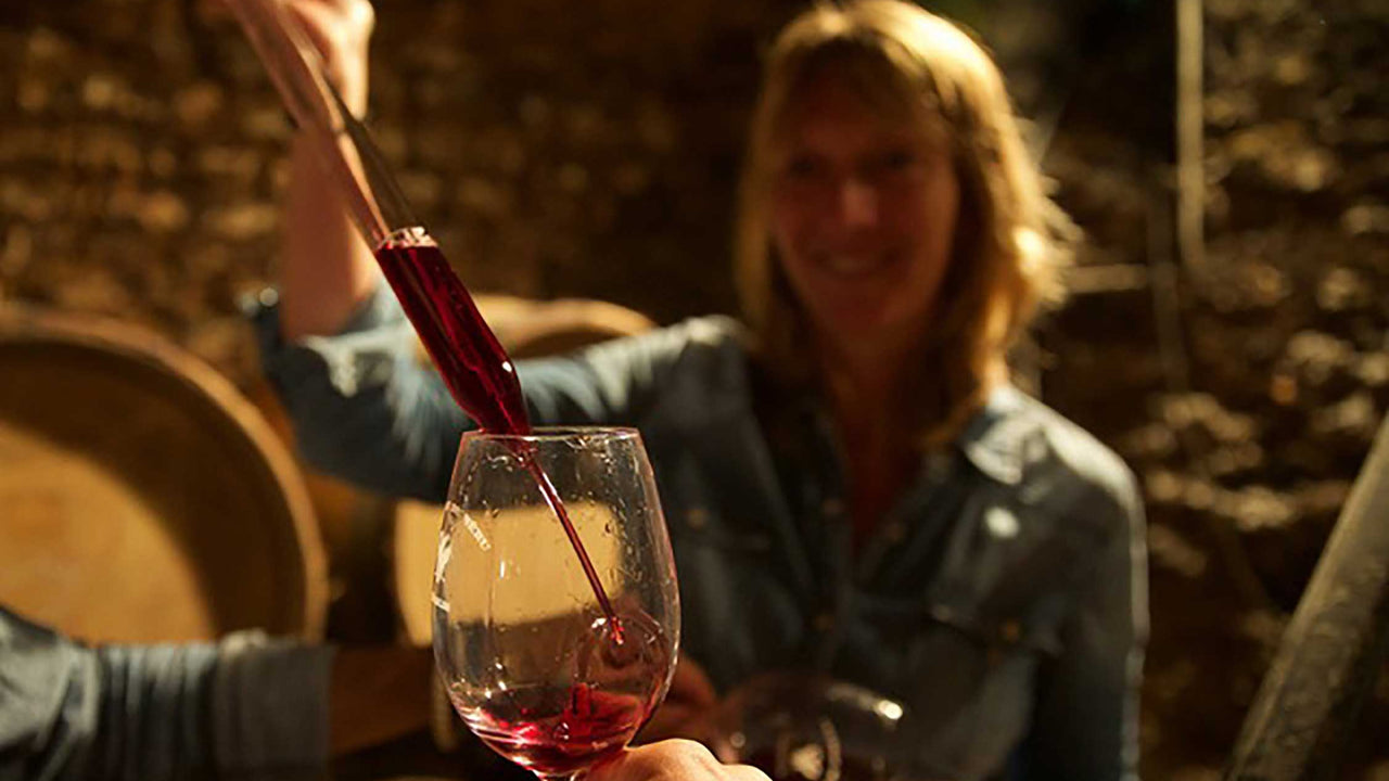 A winemaker tests wine in her wine cellar