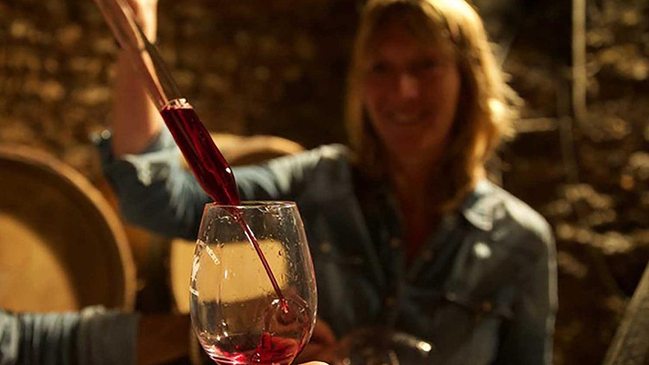 Vintner uses a glass pipe to add wine into a glass