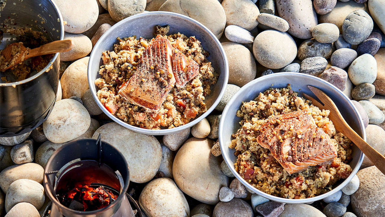 Ceramic bowls filled with Patagonia Provisions Wild Salmon and Savory Grains rest on a rocky beach