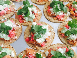 Small salmon tostadas topped with queso fresco and bright green cilantro leaves