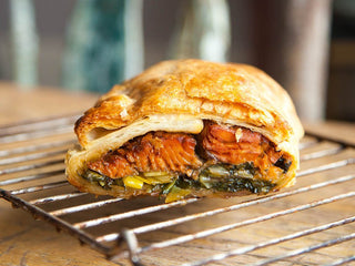 Beautiful golden puff pastry pocket filled with greens and salmon cooling on a rack