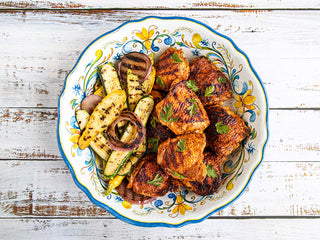 Bowl of Aji Achiote Chicken and grilled vegetables on a wooden table