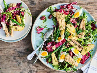 Colorful salad on a blue plate with Mackerel, potatoes, hard-boiled eggs and greens