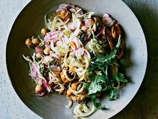 A grey ceramic dish is filled with salad made with Patagonia Provisions Smoked Mussels, chickpeas, fennel, and vinaigrette