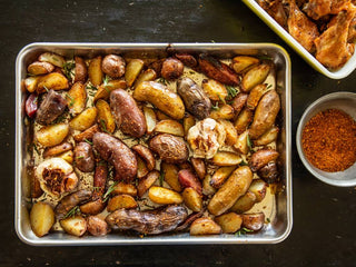 Pan of roasted fingerling potatoes next to bowl of aji molido chile in a metal bowl