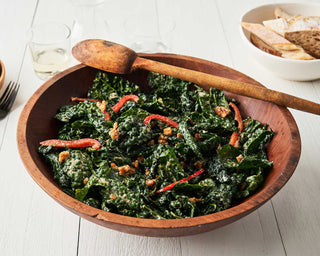 A large wooden bowl is filled with Kale Caesar Salad made with Patagonia Provisions Anchovies