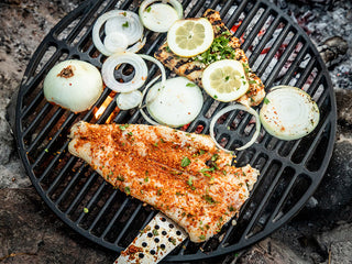 Rockfish seasoned with Patagonia Provisions Aji Molido chile, lime, and butter, cooks beside onion and lemon slices on a grill