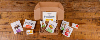 Open gift box from Patagonia Provisions with products overflowing onto a wooden table