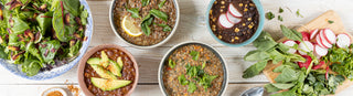 Bowls of Patagonia Provisions organic soups, chili, savory grains, sit alongside other gut healthy foods on a wooden table