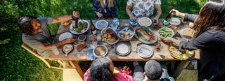 Friends gather around an outdoor table covered with dishes of Patagonia Provisions food