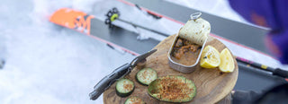 Winter ski break with open tin of Patagonia Provisions mussels, avocado and cucumber slices with spice on small board