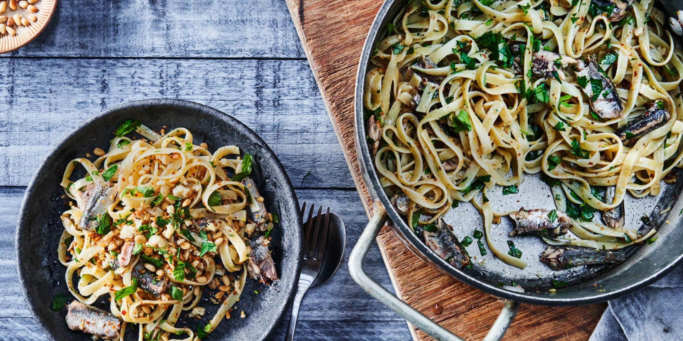 A metal pan and bowl filled with Patagonia Provisions Spanish White Anchovies with linguine and toasted breadcrumbs