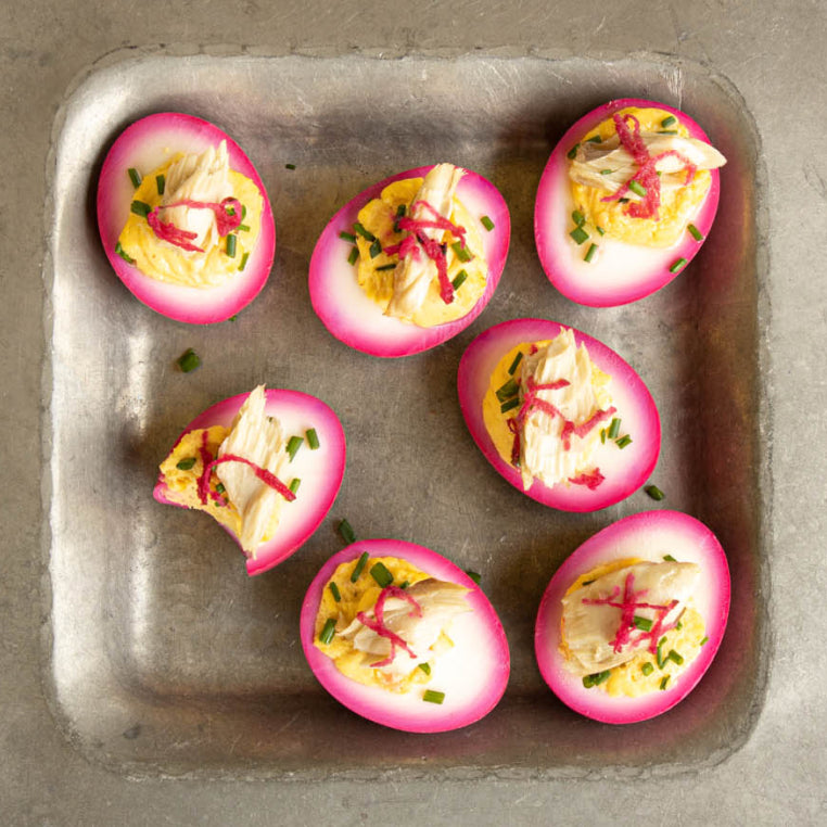 A square serving plate displays pink-tinged deviled eggs topped with Patagonia Provisions mackerel