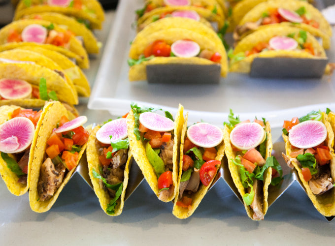 Rows of hard shelled tacos are filled with Patagonia Provisions Wild Smoked Salmon and fresh vegetables, set out for a party