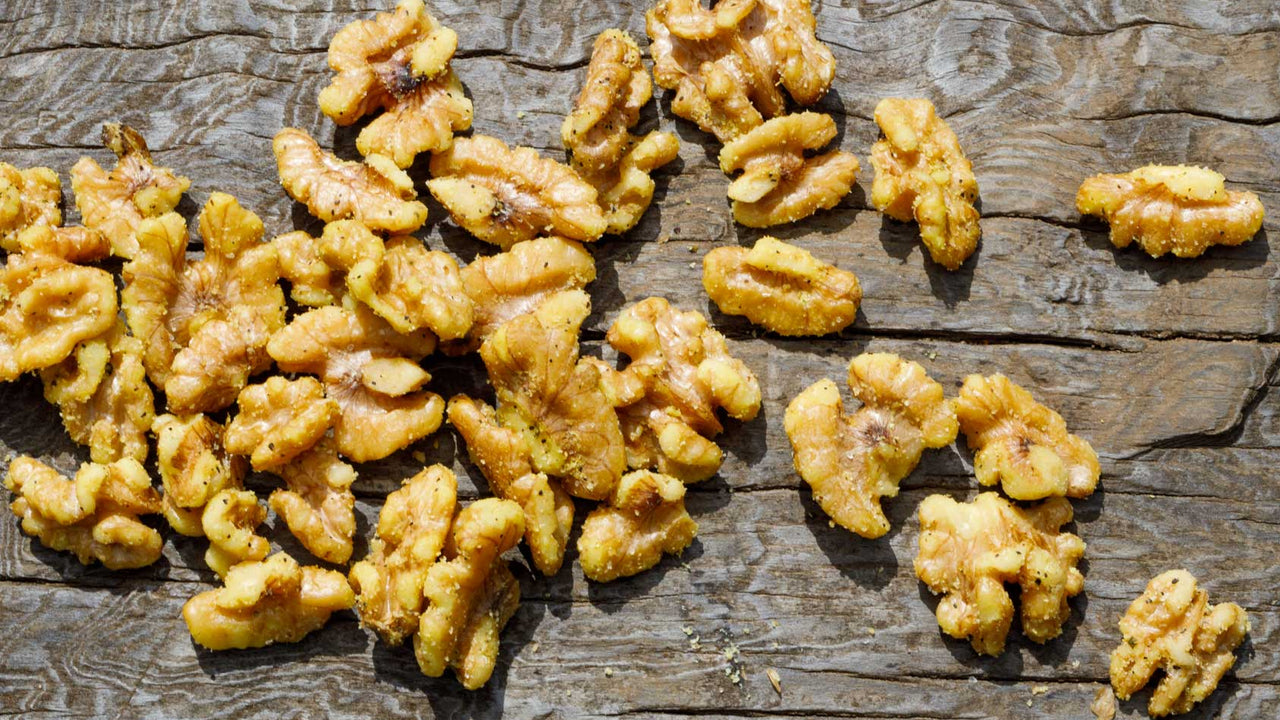 A pile of spiced golden walnuts on a cracked wooden table