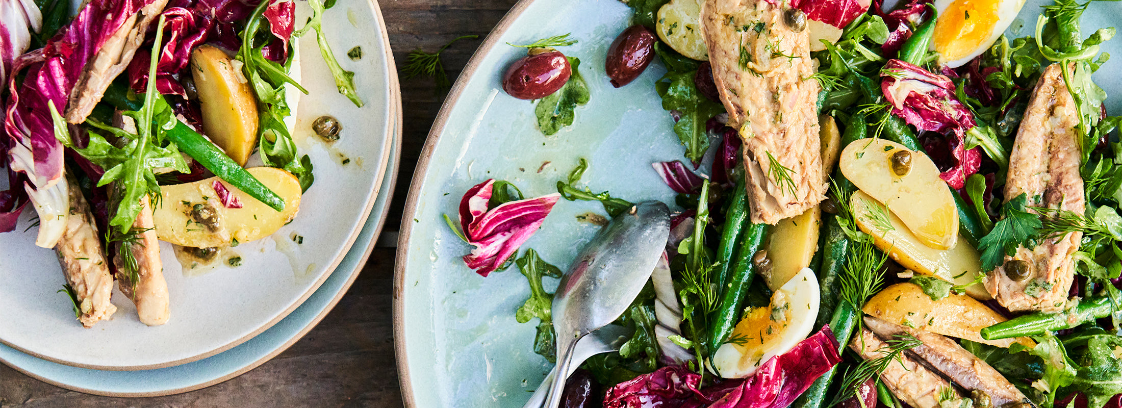 Close shot of ceramic plates with Mackerel Nicoise salad
