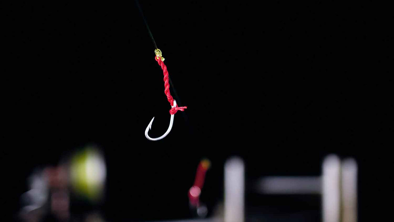 A close shot of a fishing hook tied with red thread