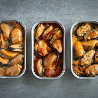 Three open cans of Provisions mussels in smoked, savory sofrito and lemon herb flavors